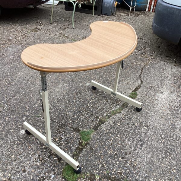 Adjustable wheelchair table with metal frame and laminate top.