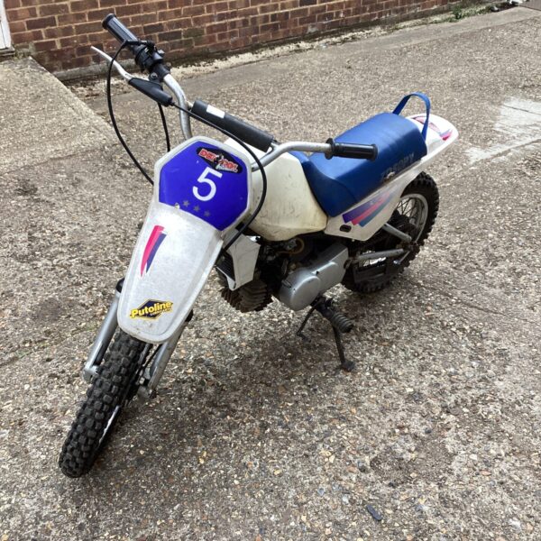 Red and white child’s motocross bike, side view.