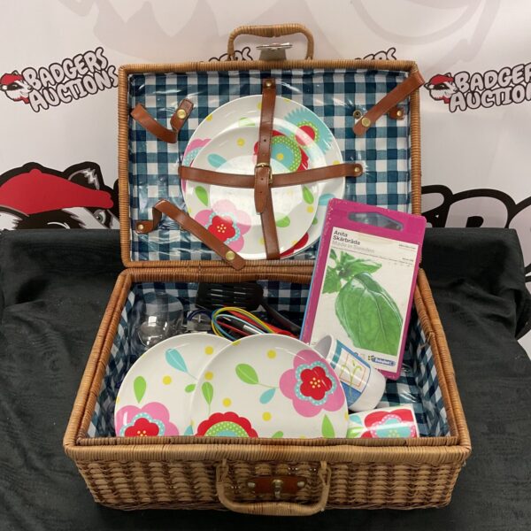 Vintage wicker picnic basket filled with plates and dining items.