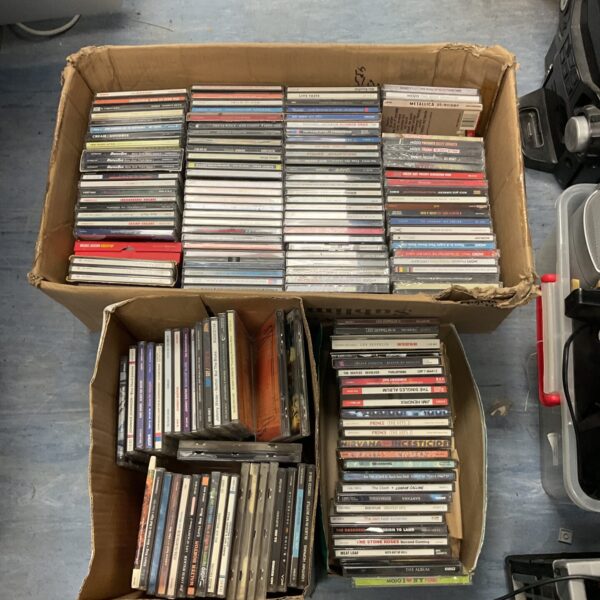 Assorted music CDs in a cardboard box, a large music lot.