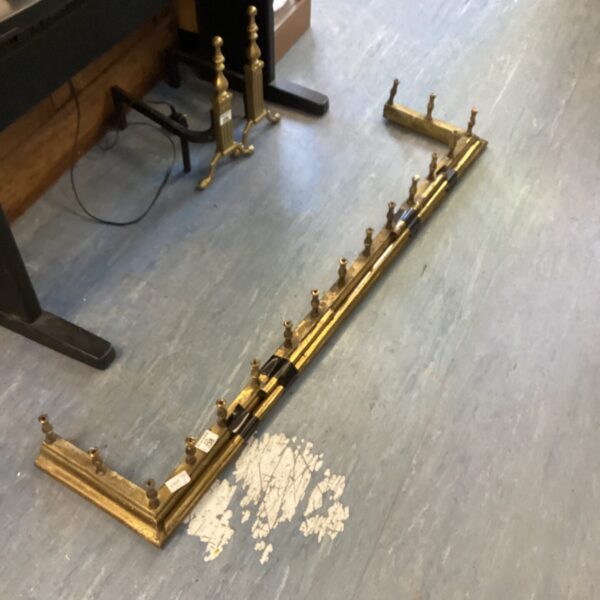 Vintage brass fireplace fender with decorative posts.