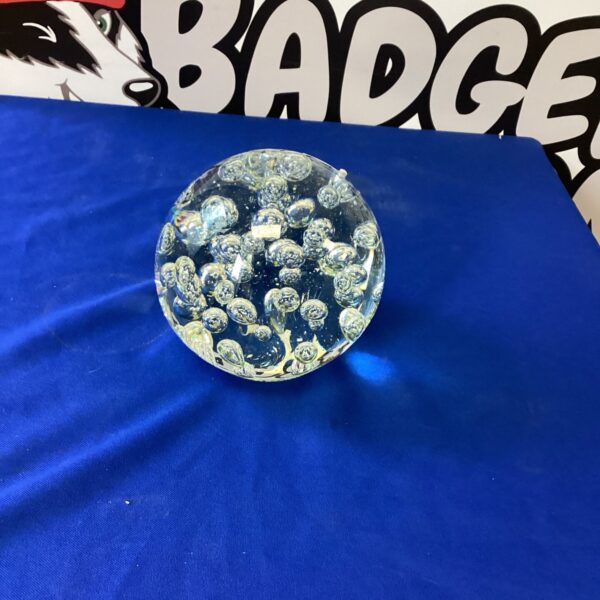 Clear glass paperweight with internal bubbles and inclusions.