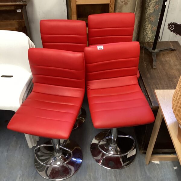 Set of four red leather bar stools with chrome bases.