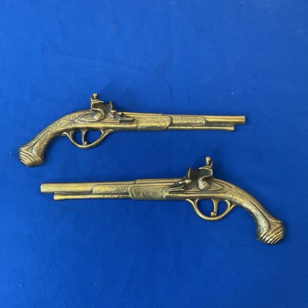 Pair of vintage brass wall hanging pistols for decorative use.