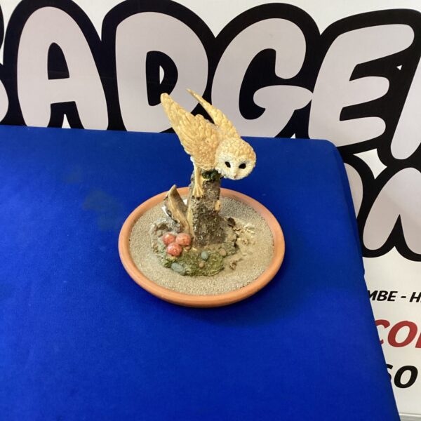 Detailed owl figurine on a rock base, vintage bird sculpture.