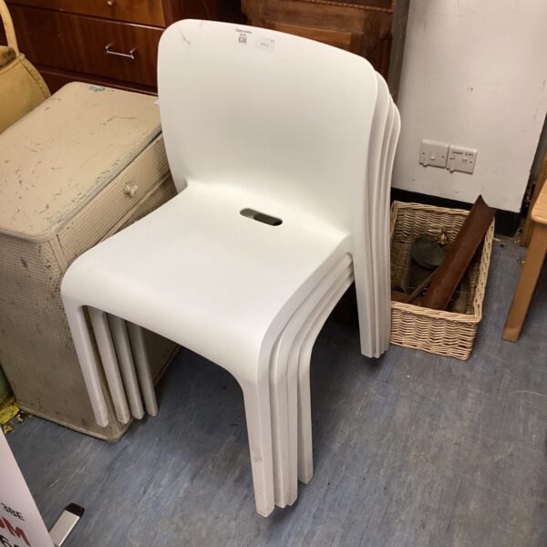 Set of four white plastic reception chairs in a waiting room setting.