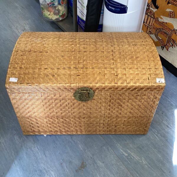 Front view of a vintage wicker trunk with a hinged lid.
