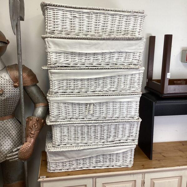 Set of six white wicker storage baskets for home organisation.