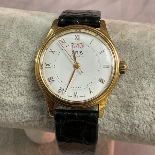 Vintage Oris wristwatch with gold case and black leather strap.