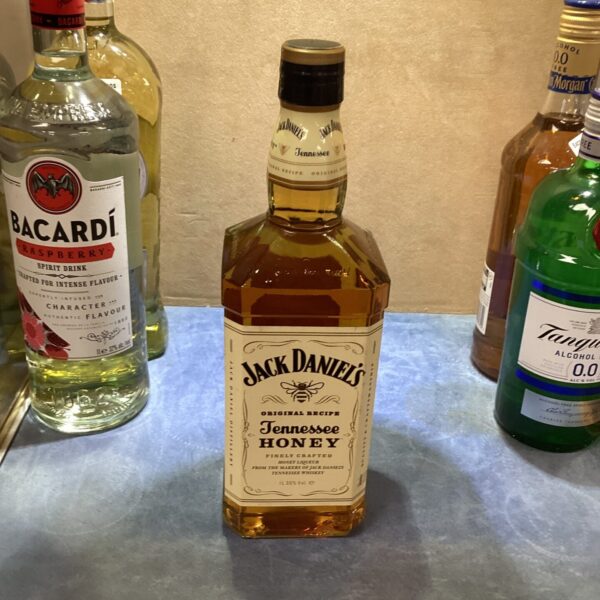 Jack Daniels Honey Whiskey bottle with other alcohol bottles in background.