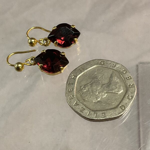 Close-up of vintage amethyst drop earrings with yellow metal settings.