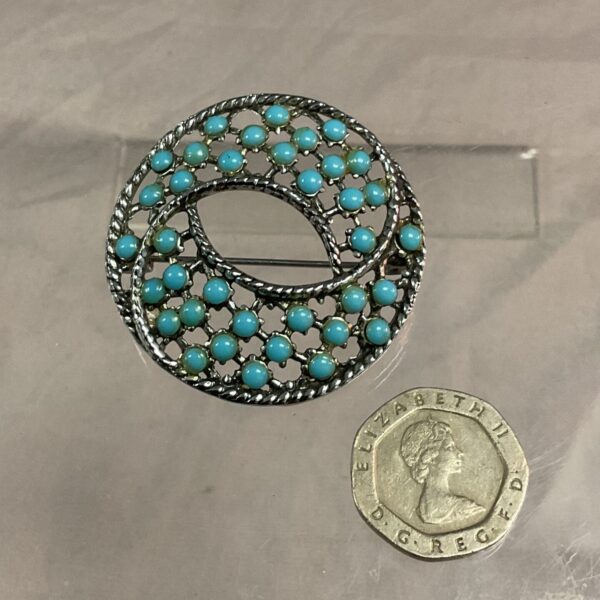 Close-up of a vintage silver tone turquoise brooch.