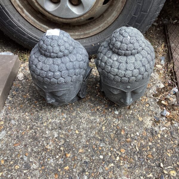 Weathered Buddha head sculpture in a garden setting.