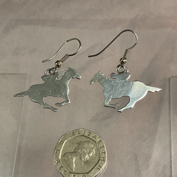 Close-up of sterling silver racehorse earrings, detailed equestrian jewelry.