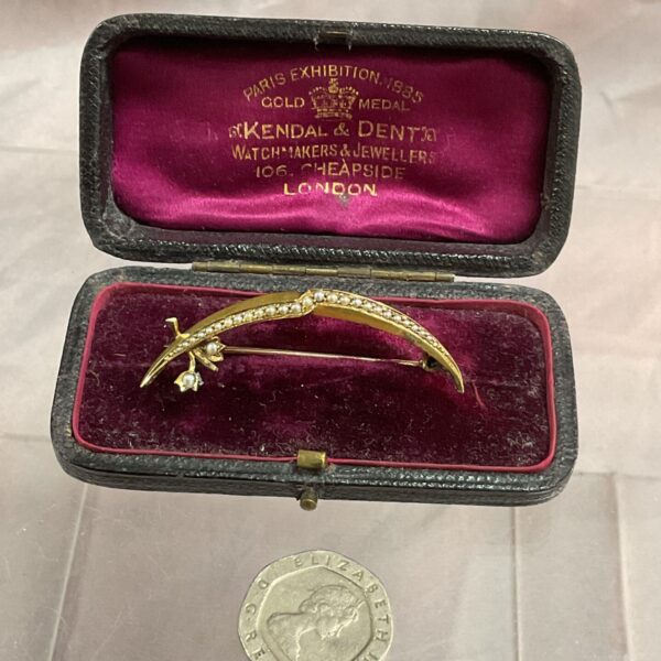 Antique Victorian seed pearl crescent brooch in a display case.