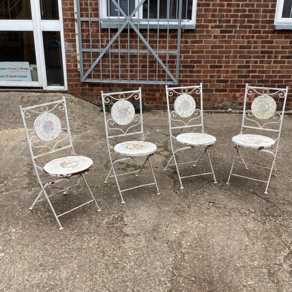 Four vintage metal garden chairs awaiting restoration in a garden setting.