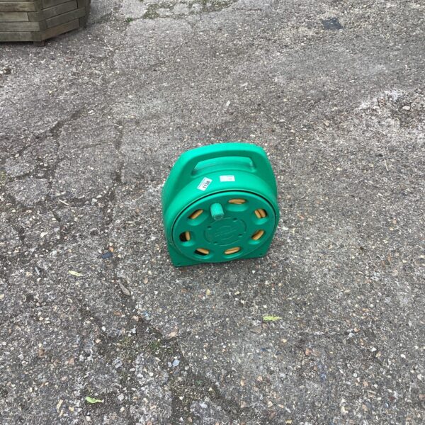 Green plastic garden hose reel for outdoor watering.