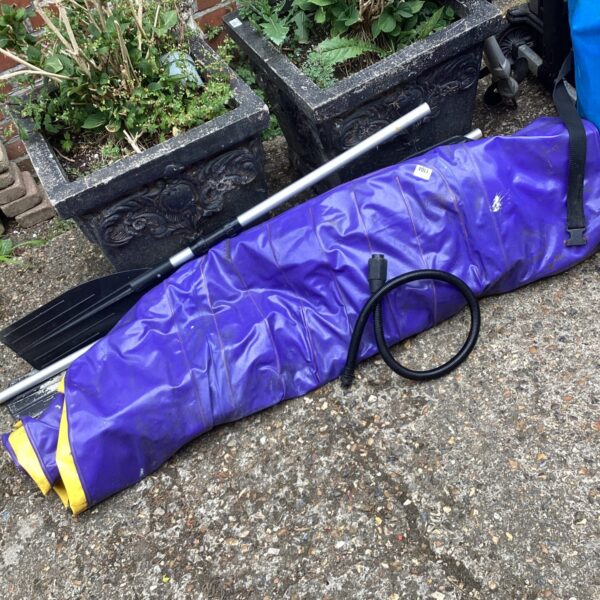 Used inflatable dinghy set with paddles for outdoor recreation.