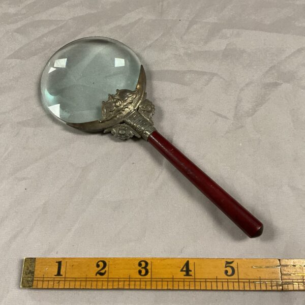 Ornate vintage magnifying glass with a decorative handle.