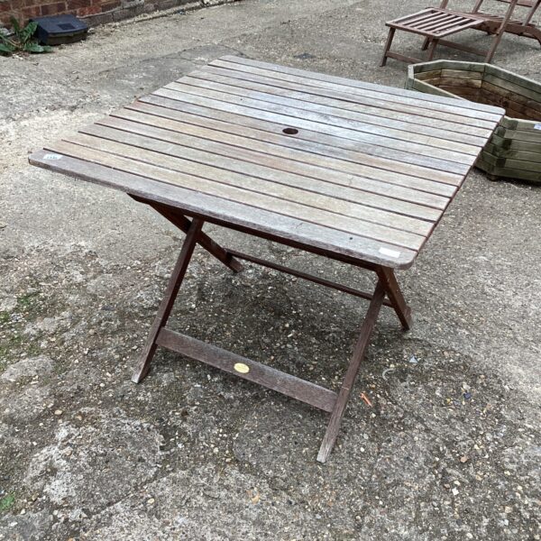 Rustic wooden folding garden table in a garden setting.