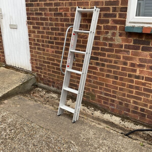 Silver aluminium loft ladder leaning against a brick wall.