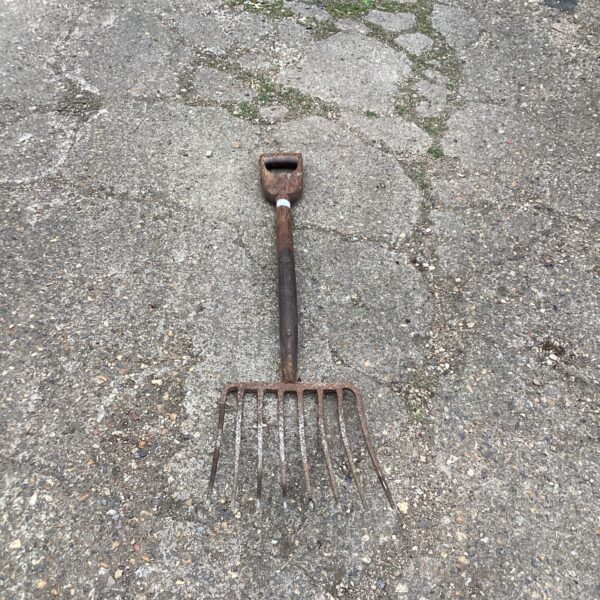 Vintage muck fork with four tines, a classic farm tool.