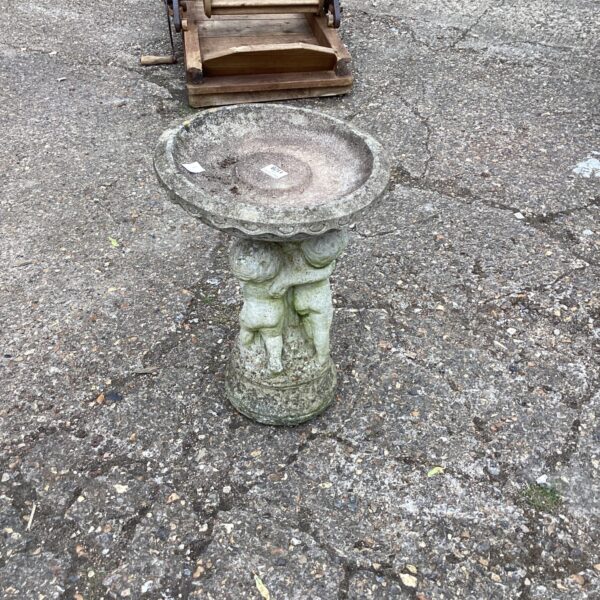 Tiered stone bird bath in a garden setting.