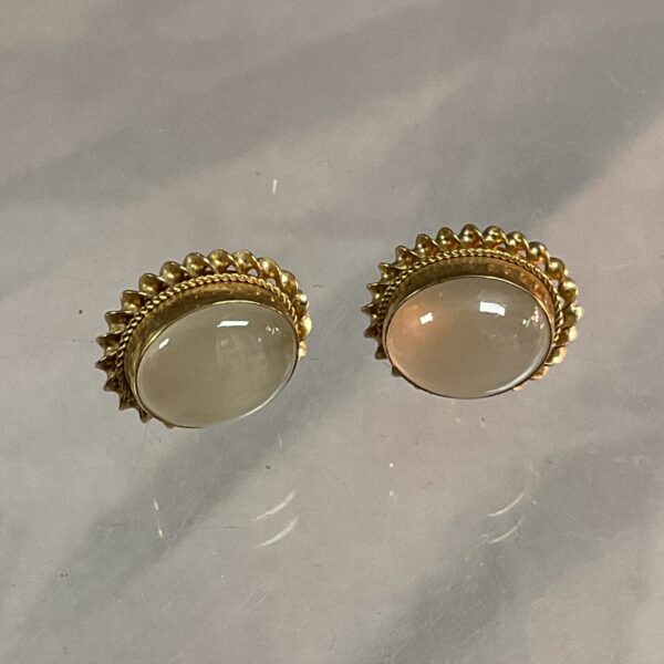 Close-up of 9ct gold moonstone stud earrings with a subtle glow.