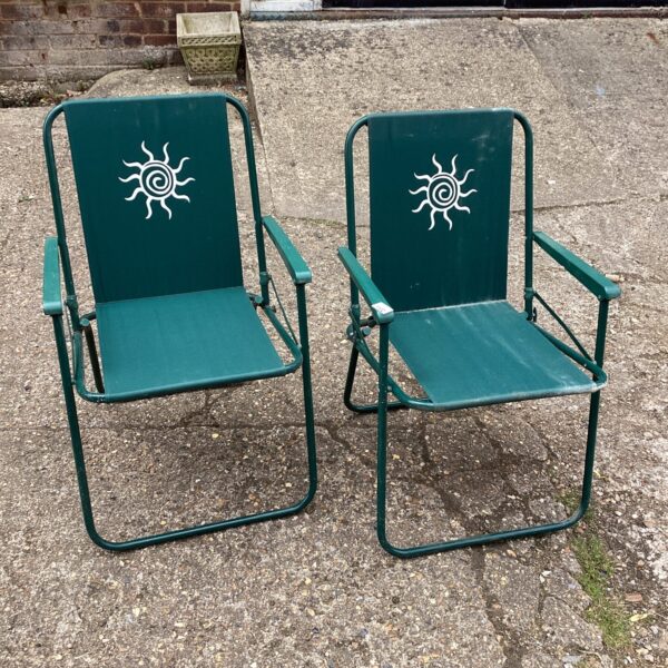 Pair of vintage folding deck chairs in a garden setting.