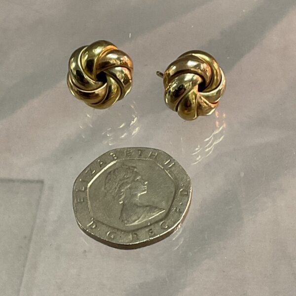 Close-up of 9ct gold knot stud earrings on a neutral background.