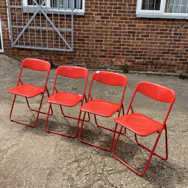 Lot of four red plastic folding chairs for events or garden use.