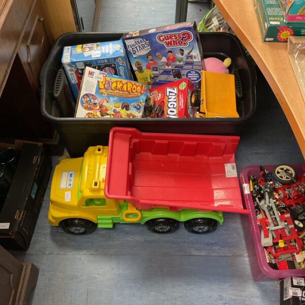 Mixed toy lot featuring a yellow dump truck and board games.