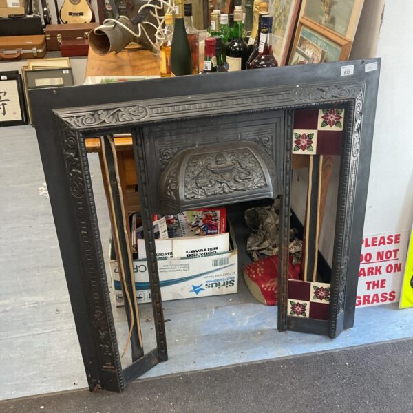 Intricate Victorian cast iron fireplace surround with floral details.