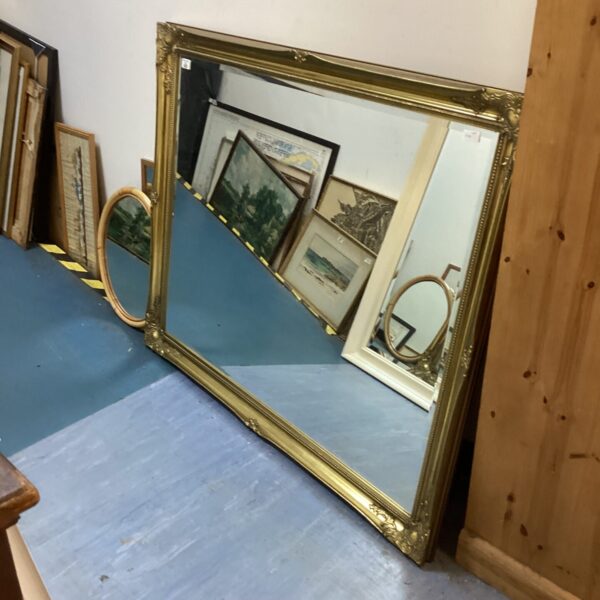 Ornate large gold gilt mirror with detailed frame.