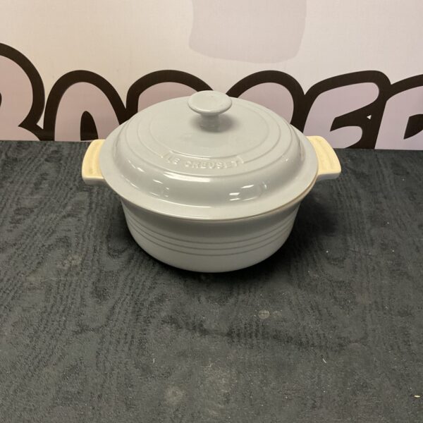 Light grey Le Creuset casserole dish on a textured surface.