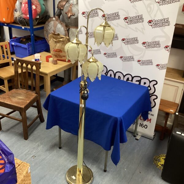 Gold standard lamp with three arms and lampshades.