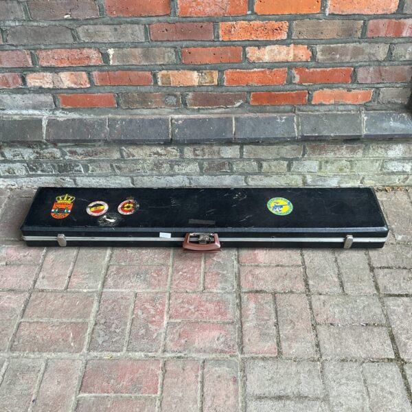 Vintage lockable gun case against brick wall.