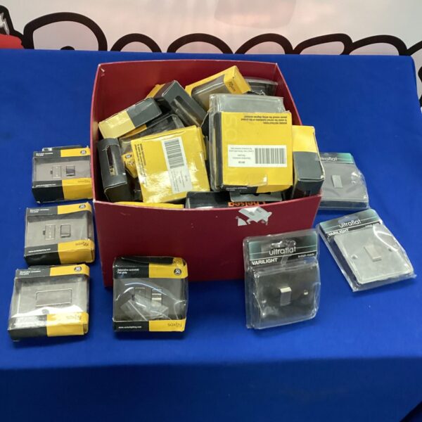 Assorted wall switches and electrical accessories in a cardboard box.