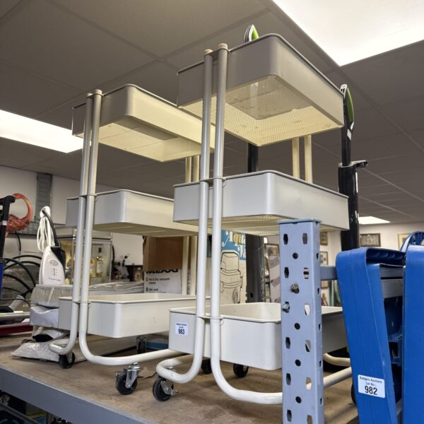 Two wheeled handy shelf units with metal frames.