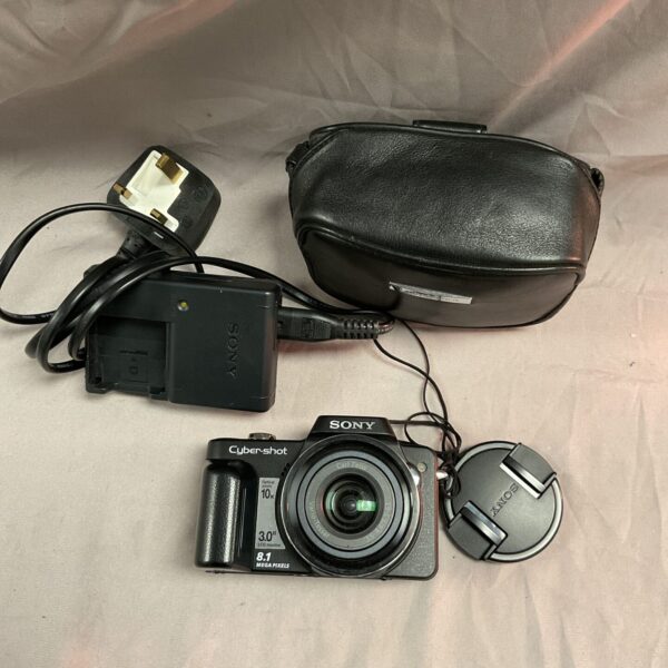 Front view of a silver Sony Cyber-shot digital camera with lens.