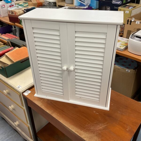 White bathroom wall cabinet with a louvered door for storage.