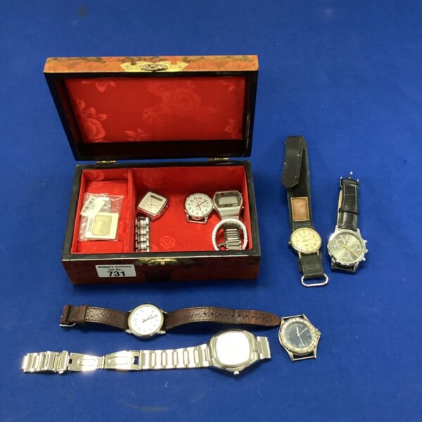 Wooden watch box with assorted vintage and modern wristwatches inside.
