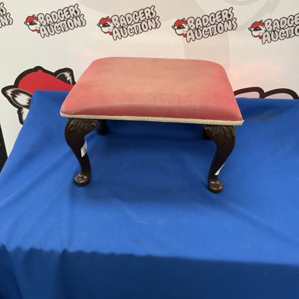 Patterned vintage footstool with wooden legs.
