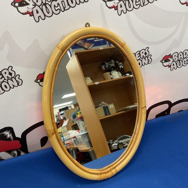 Vintage oval mirror with bamboo frame for bohemian decor.