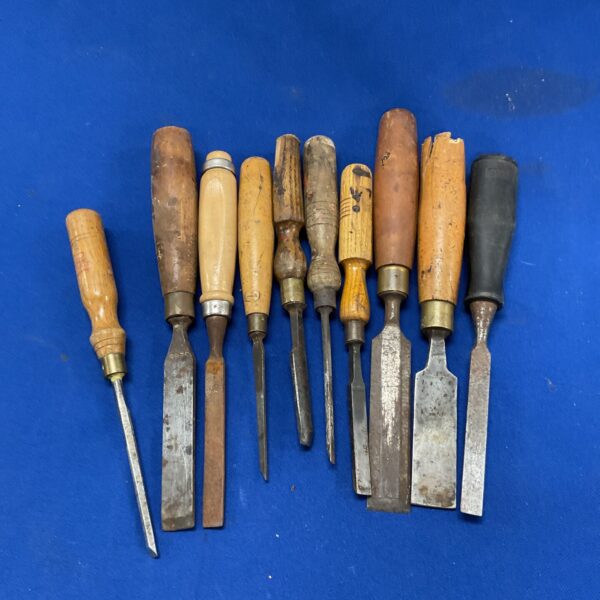 Vintage wood chisels with wooden handles in a tool lot.
