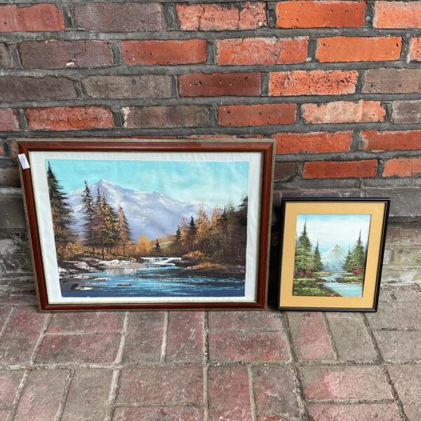Framed oil paintings of mountain river landscapes.