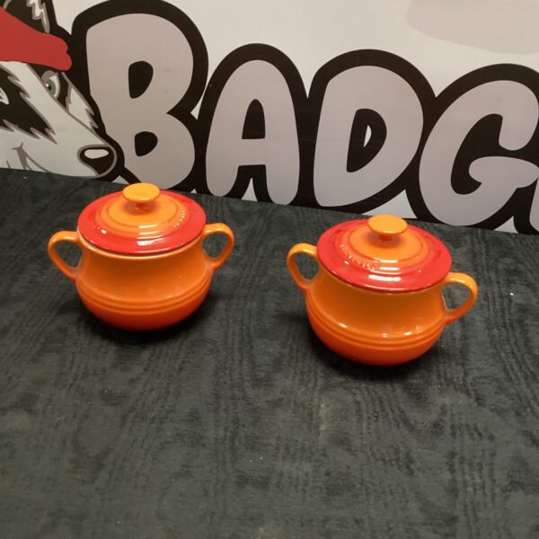 Two vibrant orange Le Creuset soup bowls on a neutral background.