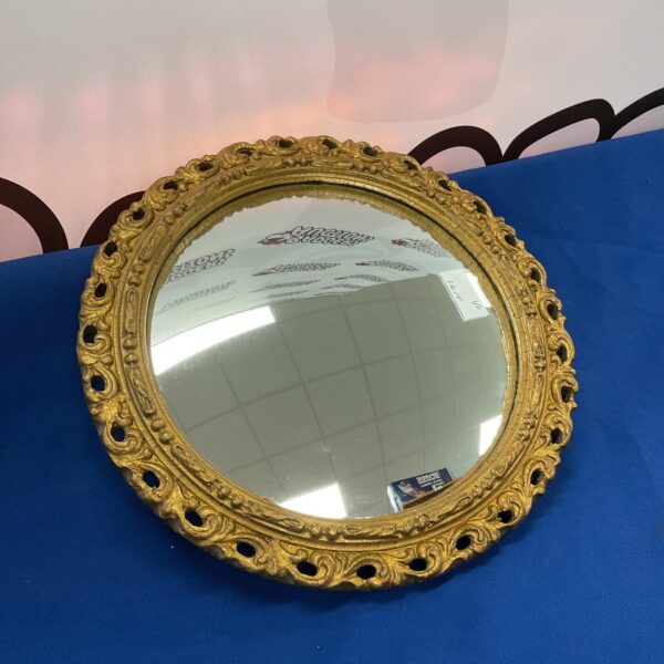 Gilt framed convex mirror with ornate detailing and a classic French style.