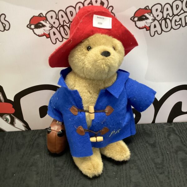 Vintage Paddington Bear toy with blue coat and red hat.