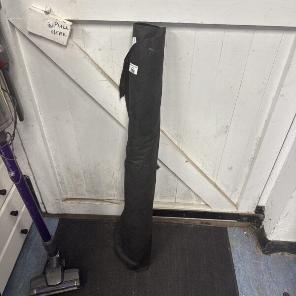 Black weed membrane roll next to a vacuum cleaner.